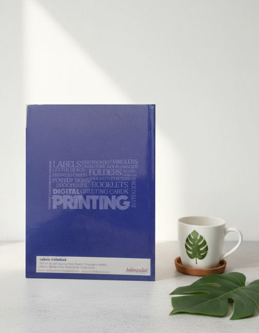 Blue printing guidebook on a white surface with a mug and plant