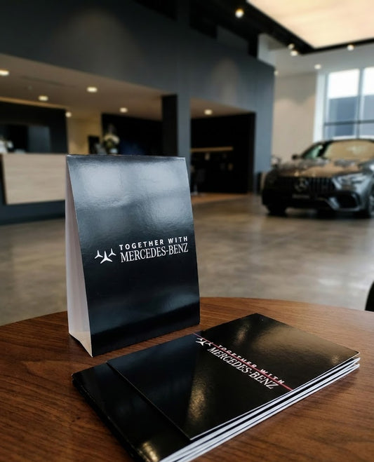 Mercedes-Benz promotional materials on a table with a car dealership in the background
