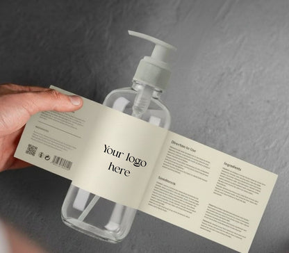 Clear bottle with pump and label held by a hand on a gray background
